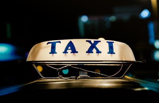 Vue rapprochée d'une enseigne de taxi illuminée dans une ville animée la nuit.